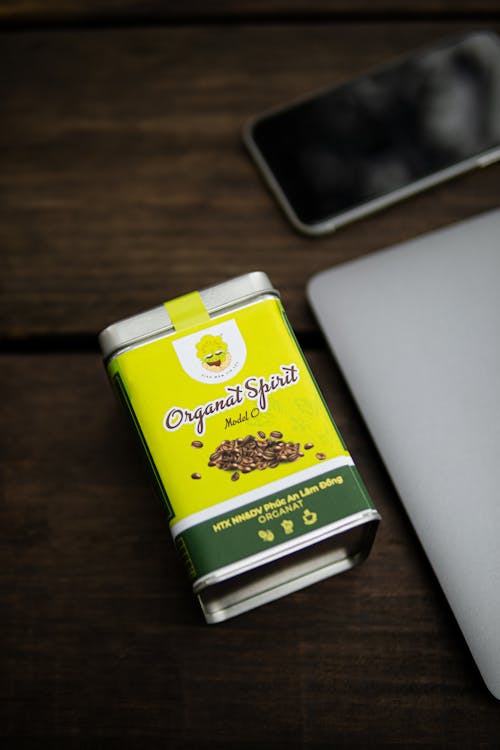 A Labeled Can on Wooden Surface Beside Modern Gadgets