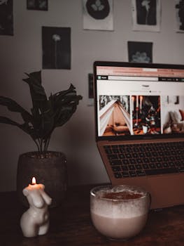 A warm and cozy workspace featuring a laptop, candle, and coffee for a relaxed atmosphere.