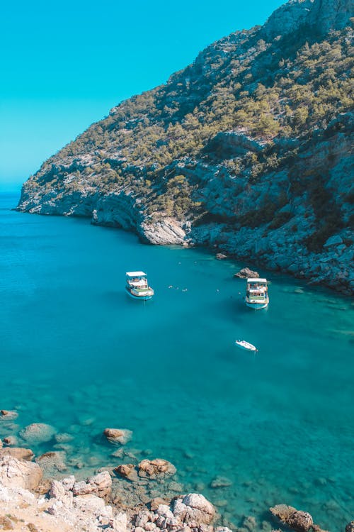 Boats Sailing on Turquoise Water by Shore