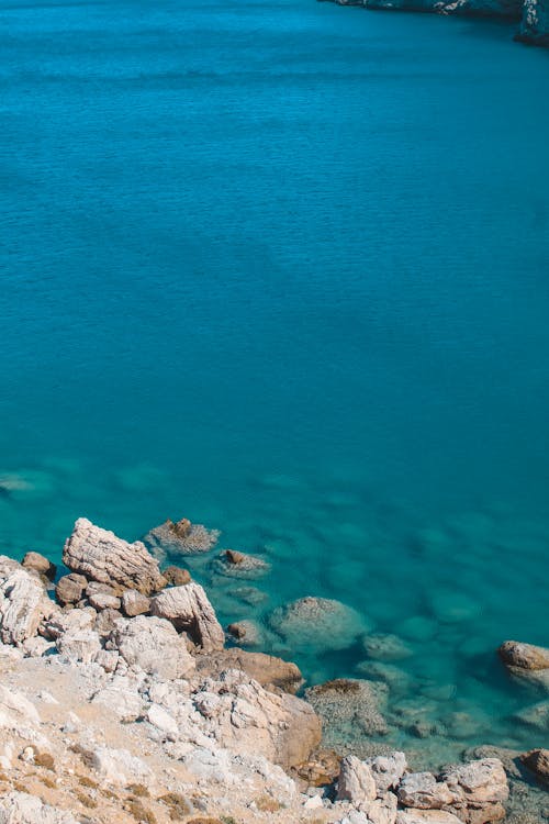 Бесплатное стоковое фото с вертикальный выстрел, голубая вода, каменистый берег