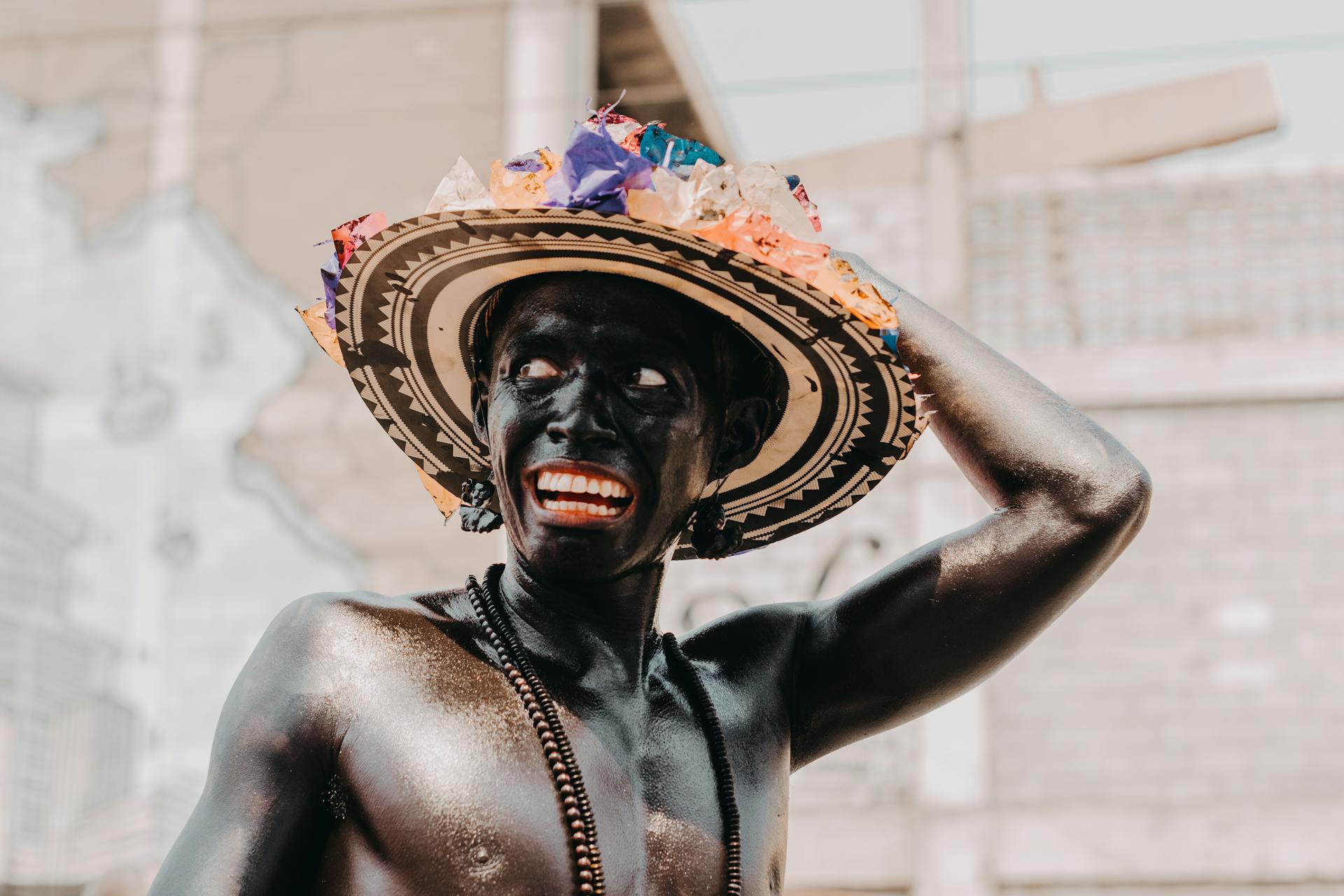 Man celebrating Barranquilla Carnival with colorful hat and body paint.