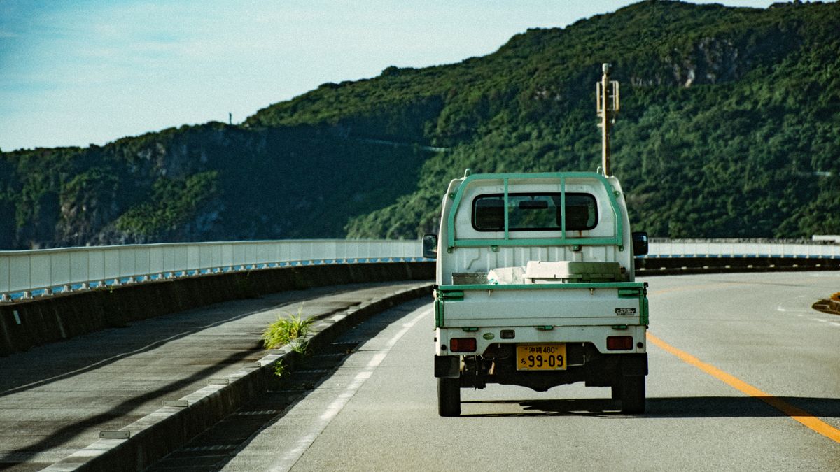沖縄の緑に囲まれた道路を走るピックアップトラック