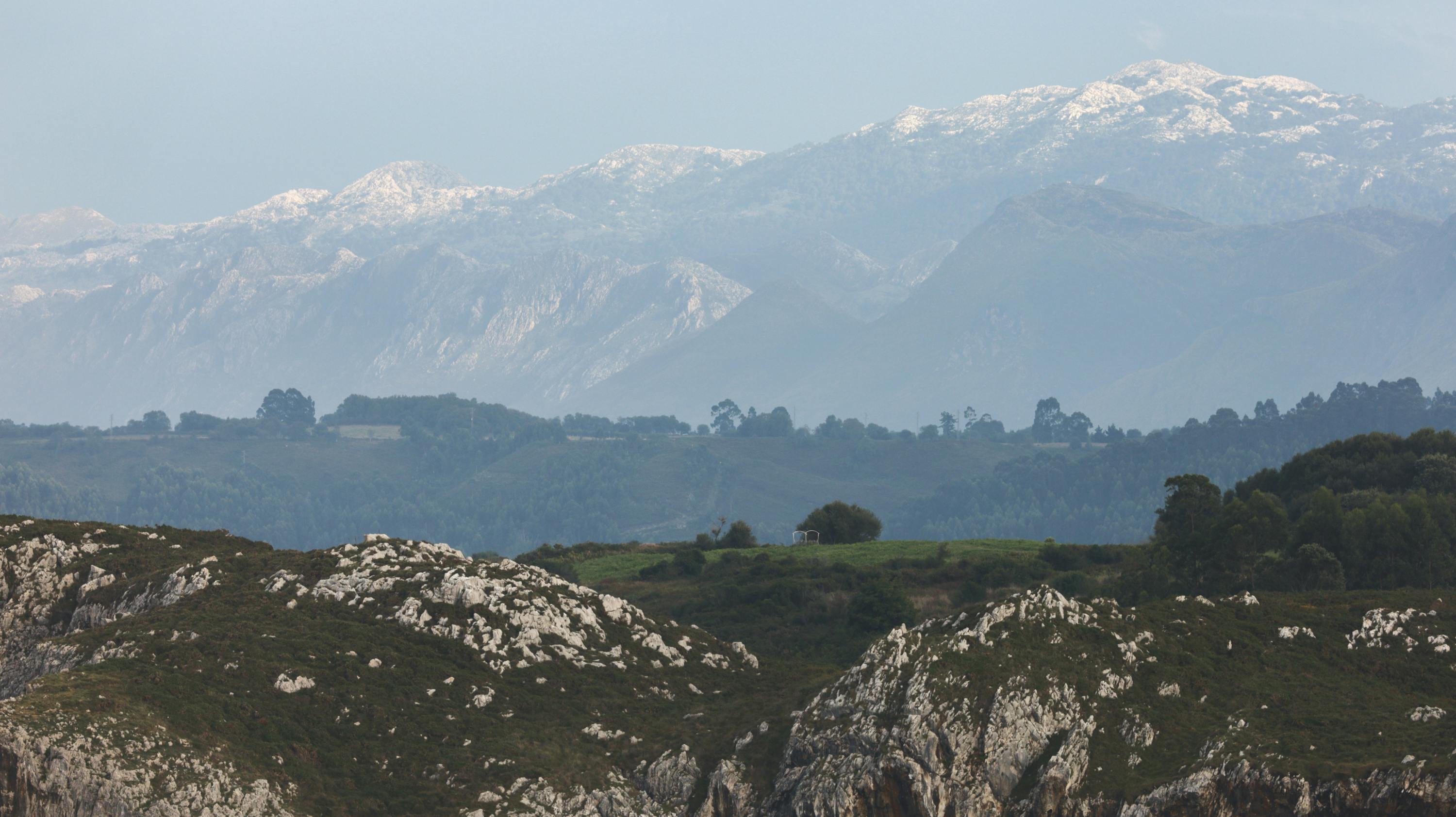A breathtaking view of snow-capped mountains and lush greenery in a peaceful natural setting.