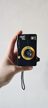 Close-up shot of a vintage analog camera held by a person, showcasing classic design.