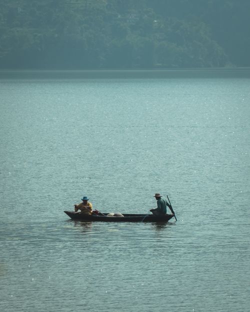 Free Two fishermen in a boat on serene Lake Phewa, Pokhara, Nepal. Stock Photo