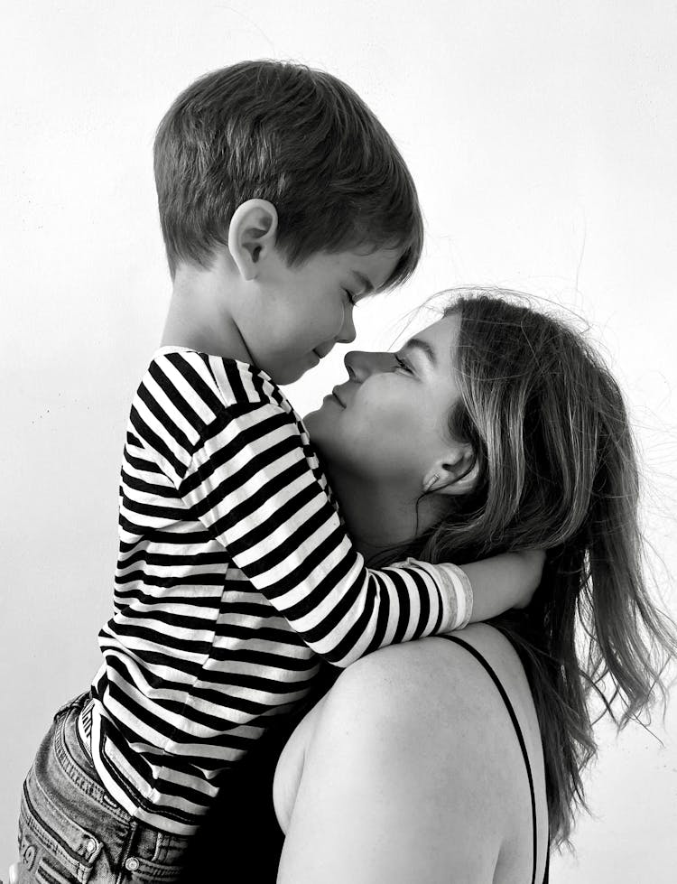 Woman In Spaghetti Strap Top Carrying And Hugging A Boy In Black And White Stripe Long Sleeve Shirt 