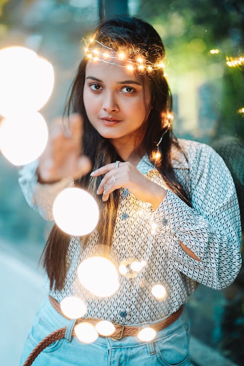 A Woman in White Long Sleeves Holding Fairy Lights