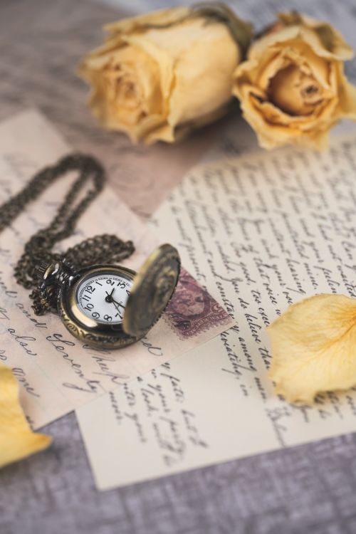 Free Elegant vintage still life featuring a pocket watch, dried roses, and handwritten letters. Stock Photo