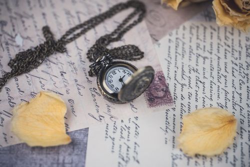 Free Antique pocket watch on old letters with dried rose petals, evoking nostalgia. Stock Photo