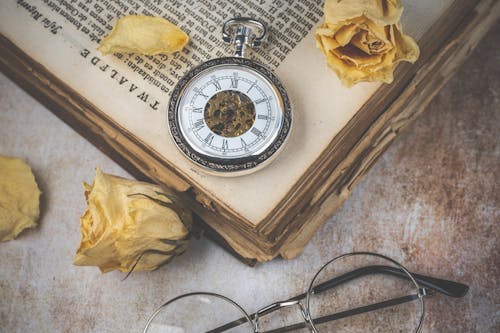 Vintage Stopwatch on a Book Among Yellow Roses 
