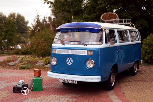 Free Classic blue Volkswagen camper van showcased outdoors with retro items under a cloudy sky. Stock Photo