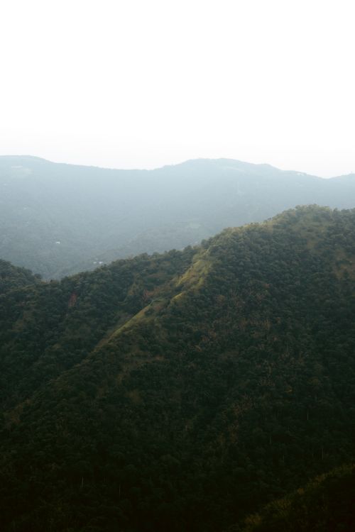 Free A serene aerial photograph capturing lush green mountains under a clear sky. Stock Photo