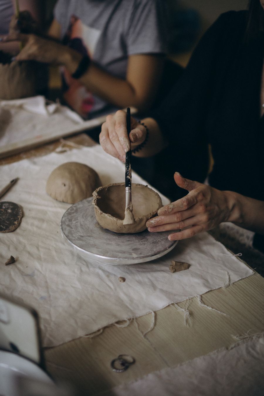 A brush laying glaze onto a hand-built clay bowl
