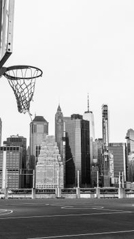 Monochrome view of a basketball hoop and New York City skyline, capturing urban athletic life.