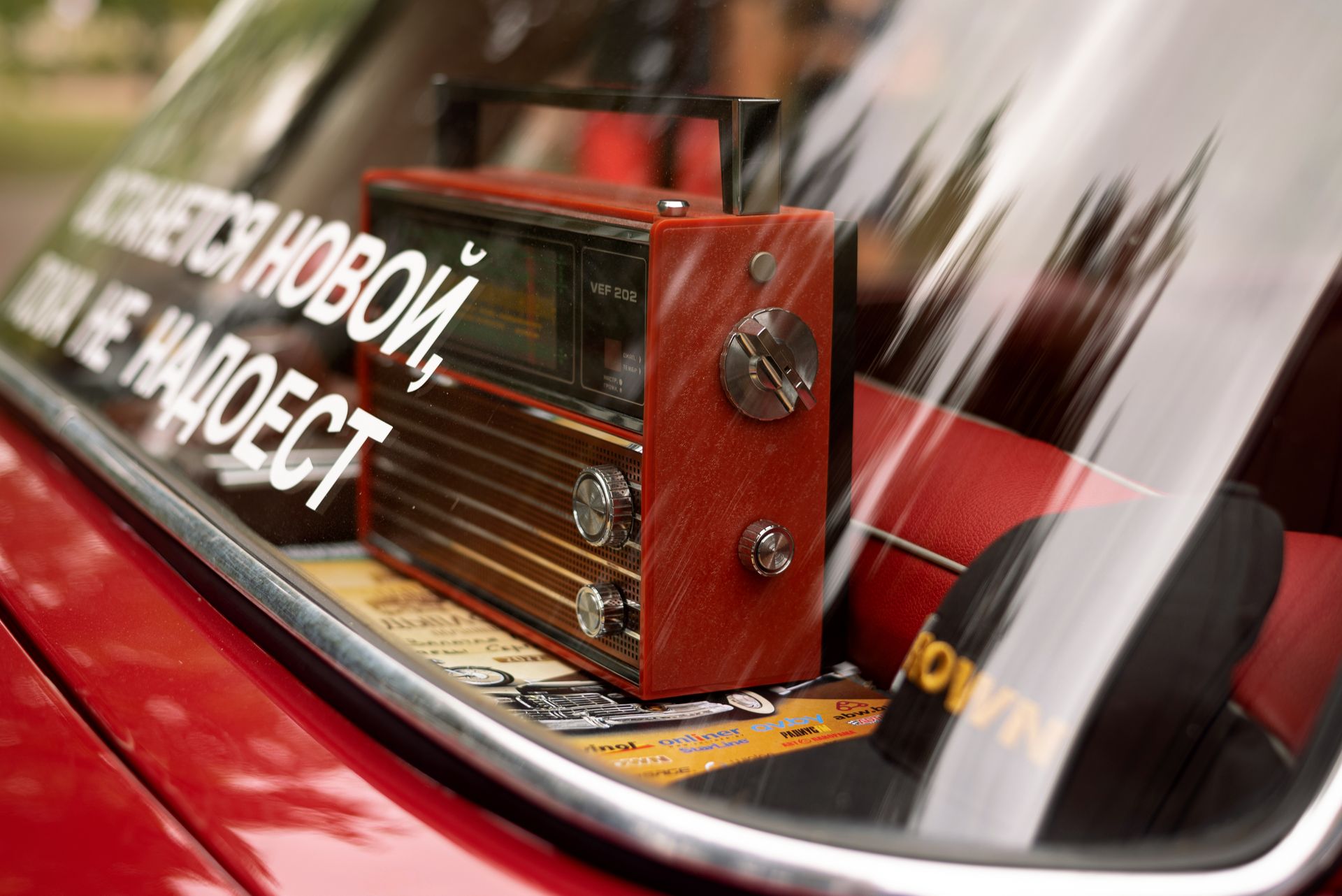Close-up of a vintage radio inside a classic car's rear window with reflective glass.