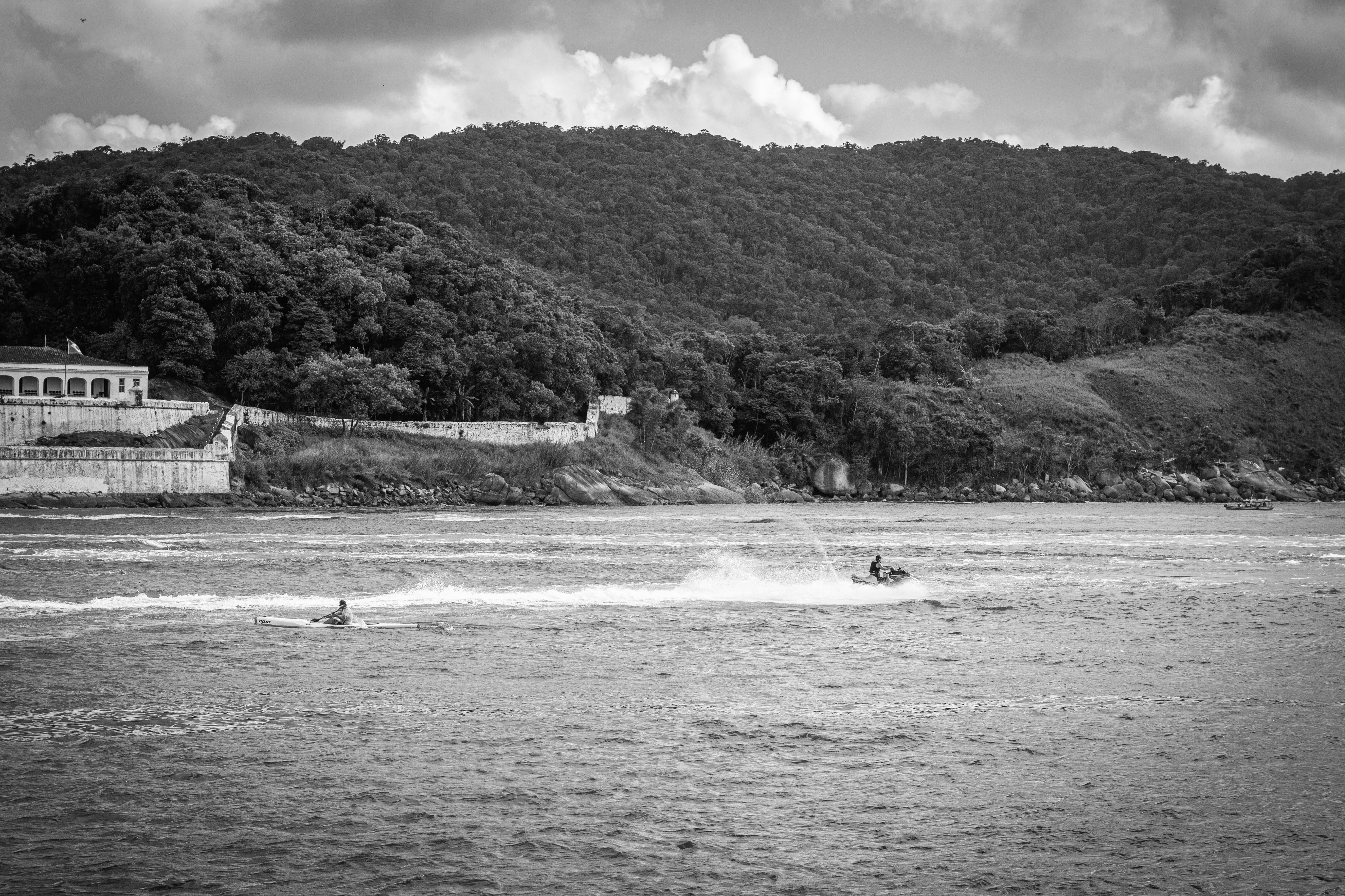 Exciting black and white photo of jet skiing near lush hills in Santos, Brazil.