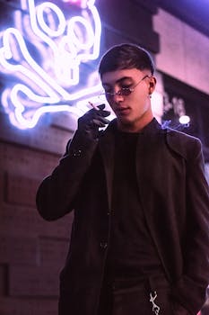 A young man in Bogotá nightlife, smoking with neon skull art in background.