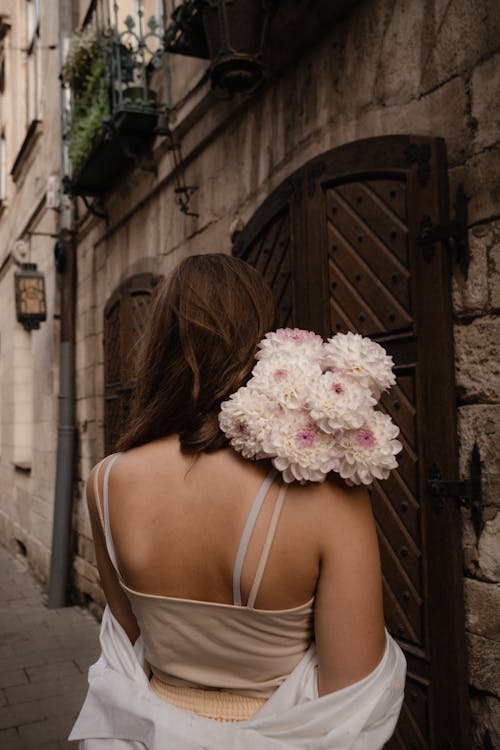 Woman in Spaghetti Strap Top Holding a Bunch of Flowers