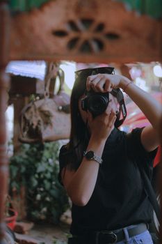 Woman in black t-shirt taking a photo outdoors, showcasing photography passion.