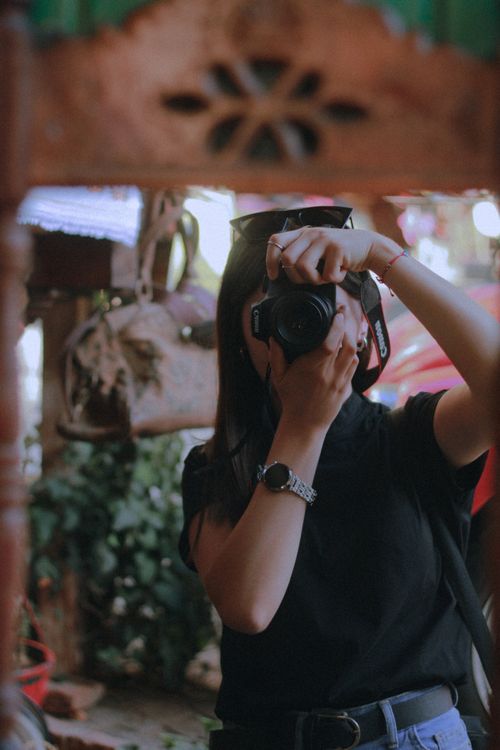 Free Woman in black t-shirt taking a photo outdoors, showcasing photography passion. Stock Photo
