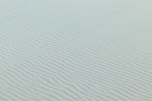 Fine rippled sand pattern under a bright sky, capturing the essence of a tranquil desert scene.