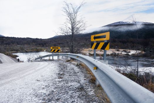 Snow-covered road with safety signage in Ushuaia, Tierra del Fuego, Argentina during winter.