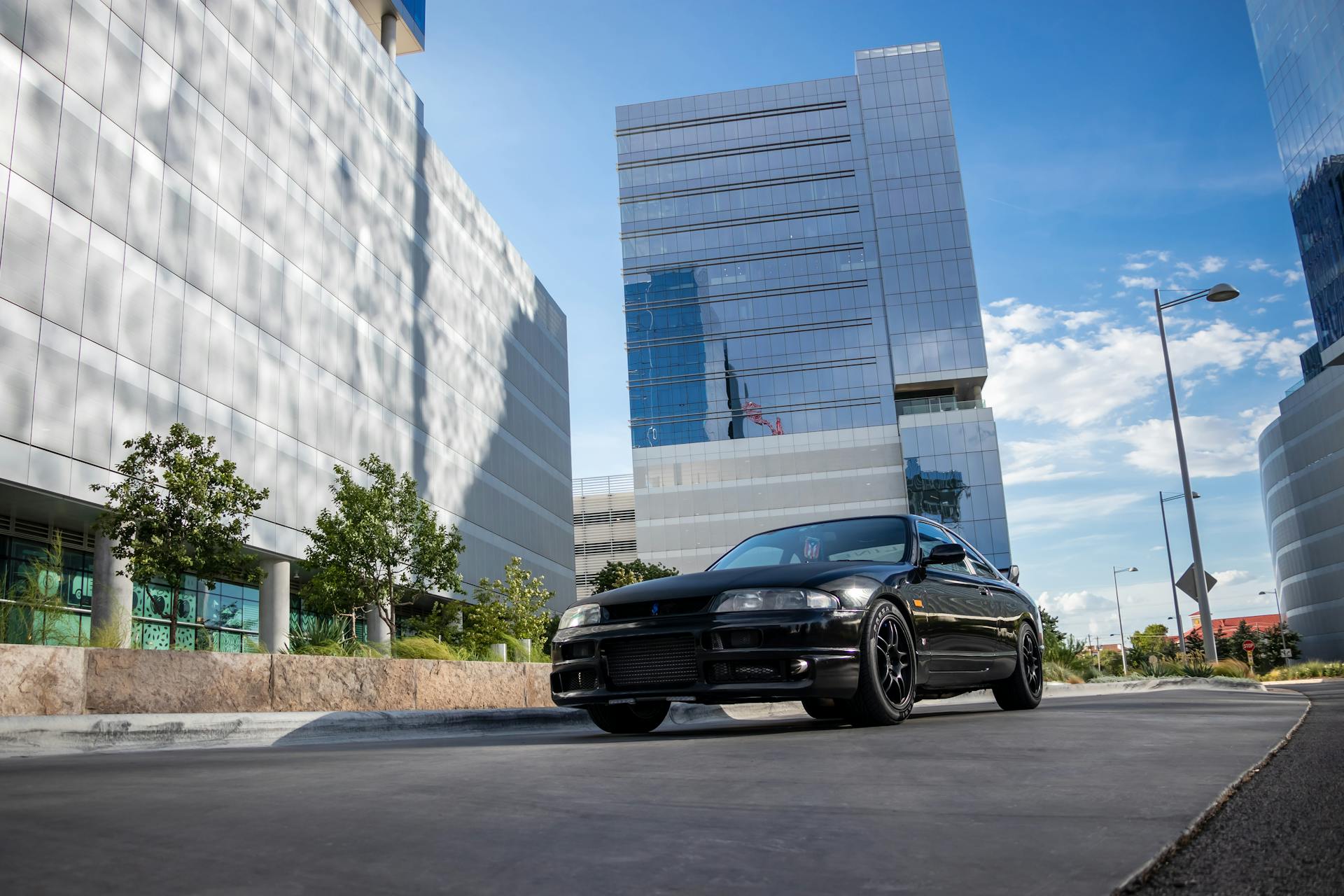 Stylish Nissan sedan parked in urban Austin with reflective skyscrapers, sunny day.