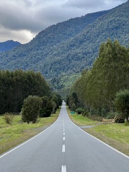 Straight road through mountain landscape in Puerto Varas, Chile, surrounded by trees and greenery.