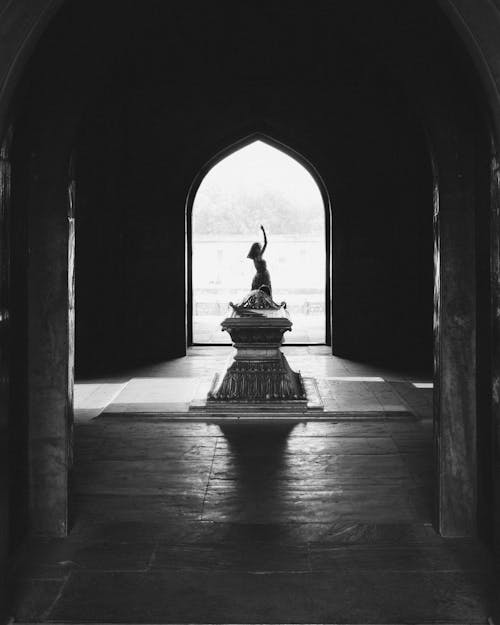 Grayscale Photo of Statue in Tunnel