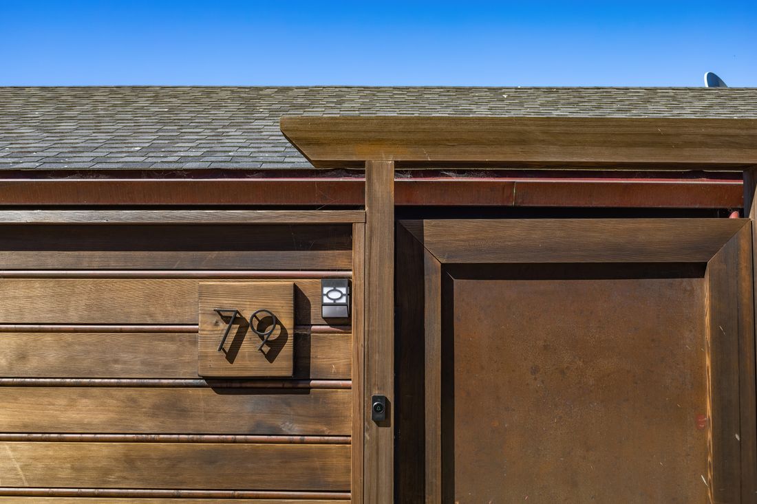 Stylish wooden door with house number 79 under clear blue sky