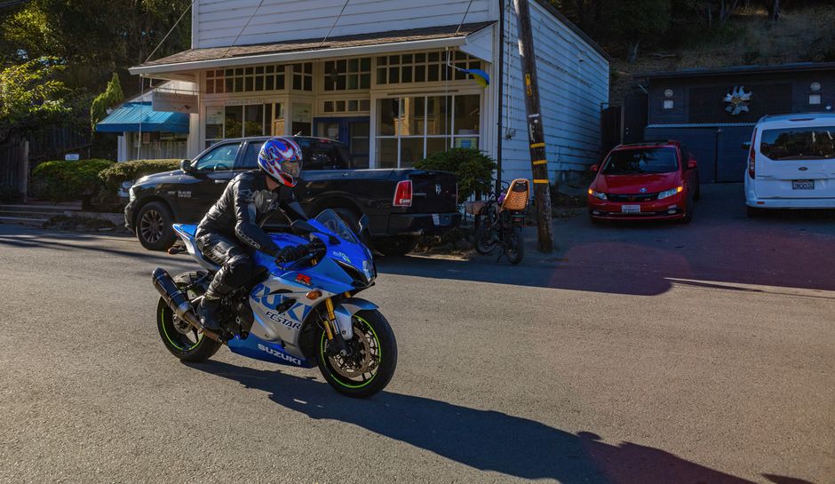 Geico vs Allstate: Motorcycle Insurance Rates for Sport Bikes & Cruisers A motorcyclist in gear rides a blue sports bike on a sunny street.
