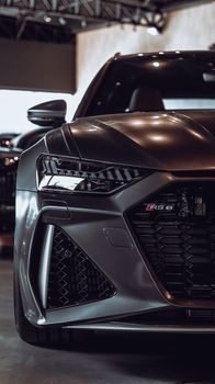 Close-up shot of a luxury Audi RS6 with shiny headlight in showroom setting.