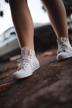 Stylish white sneakers on an outdoor city sidewalk, showcasing casual urban footwear fashion.