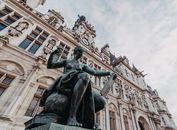Detailed view of a statue and facade at Paris's Hôtel de Ville, under a cloudy sky.