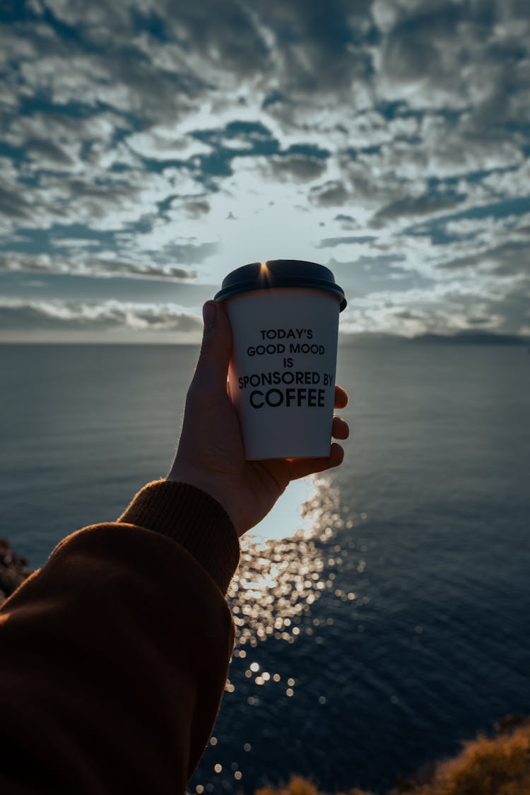 Man Hand Holding Coffee Takeaway Cup Near Water