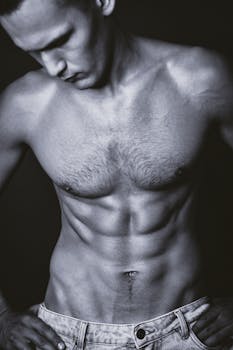 Black and white portrait of a shirtless man highlighting toned muscles.