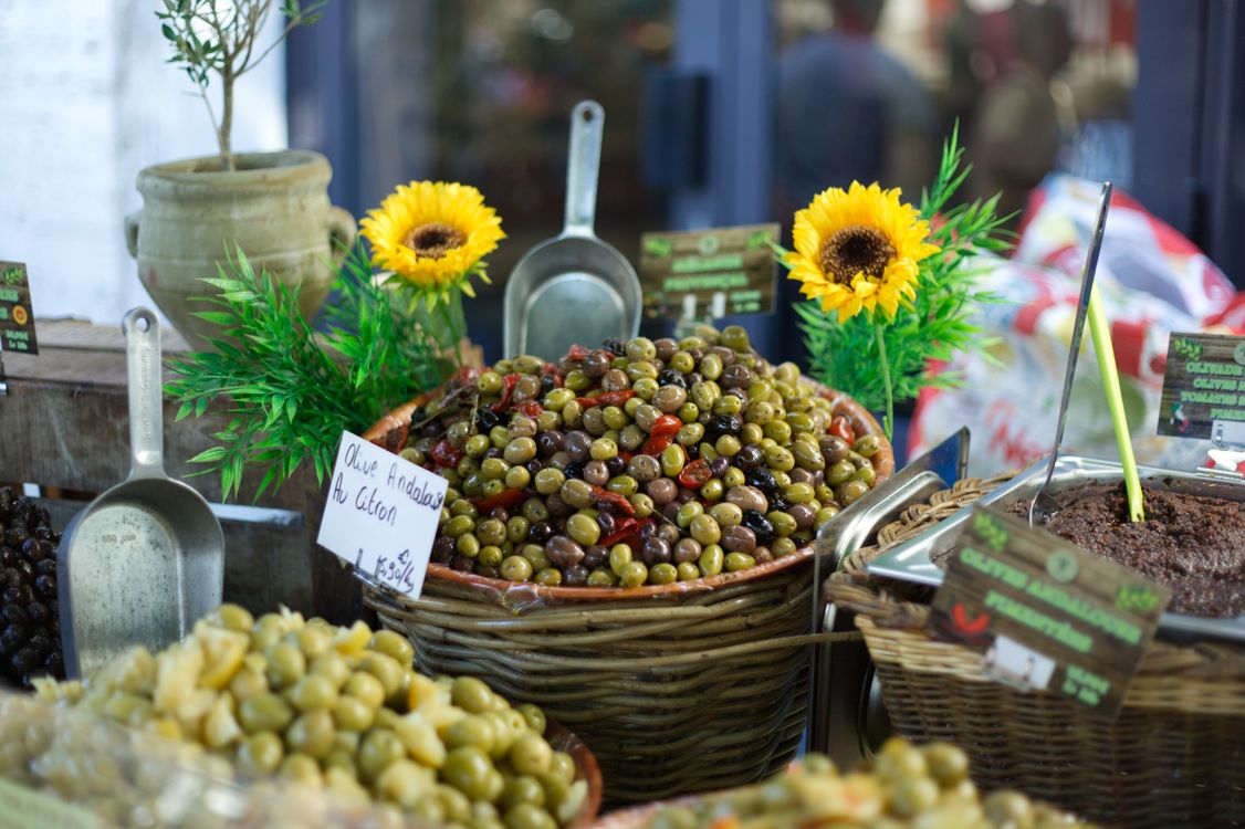 Olives fraîches sur un marché provençal authentique Panier d'olives colorées sur un étal de marché provençal en plein air