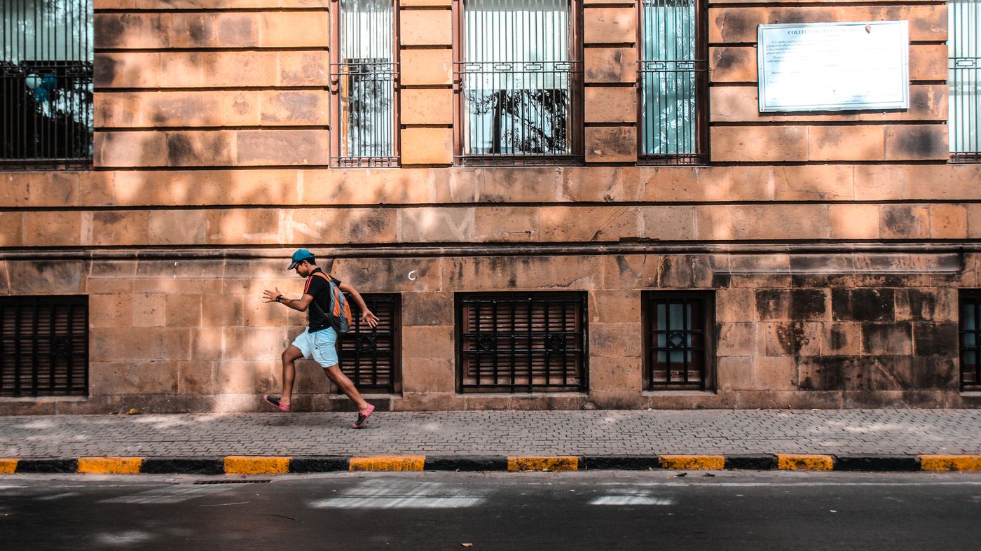 Man running past a sunlit historic sandstone building — photo by Yogendra Singh on Pexels