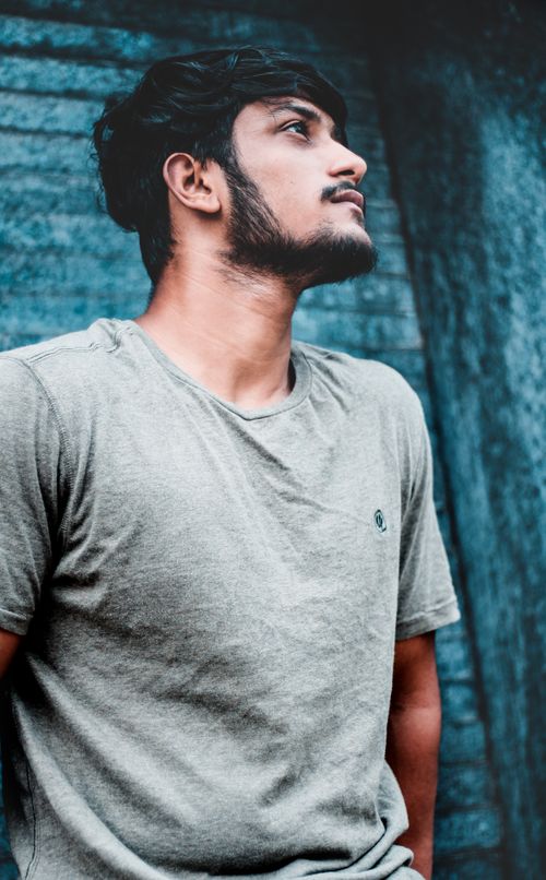 Free Close-up of a young man with facial hair wearing a casual t-shirt outdoors. Stock Photo