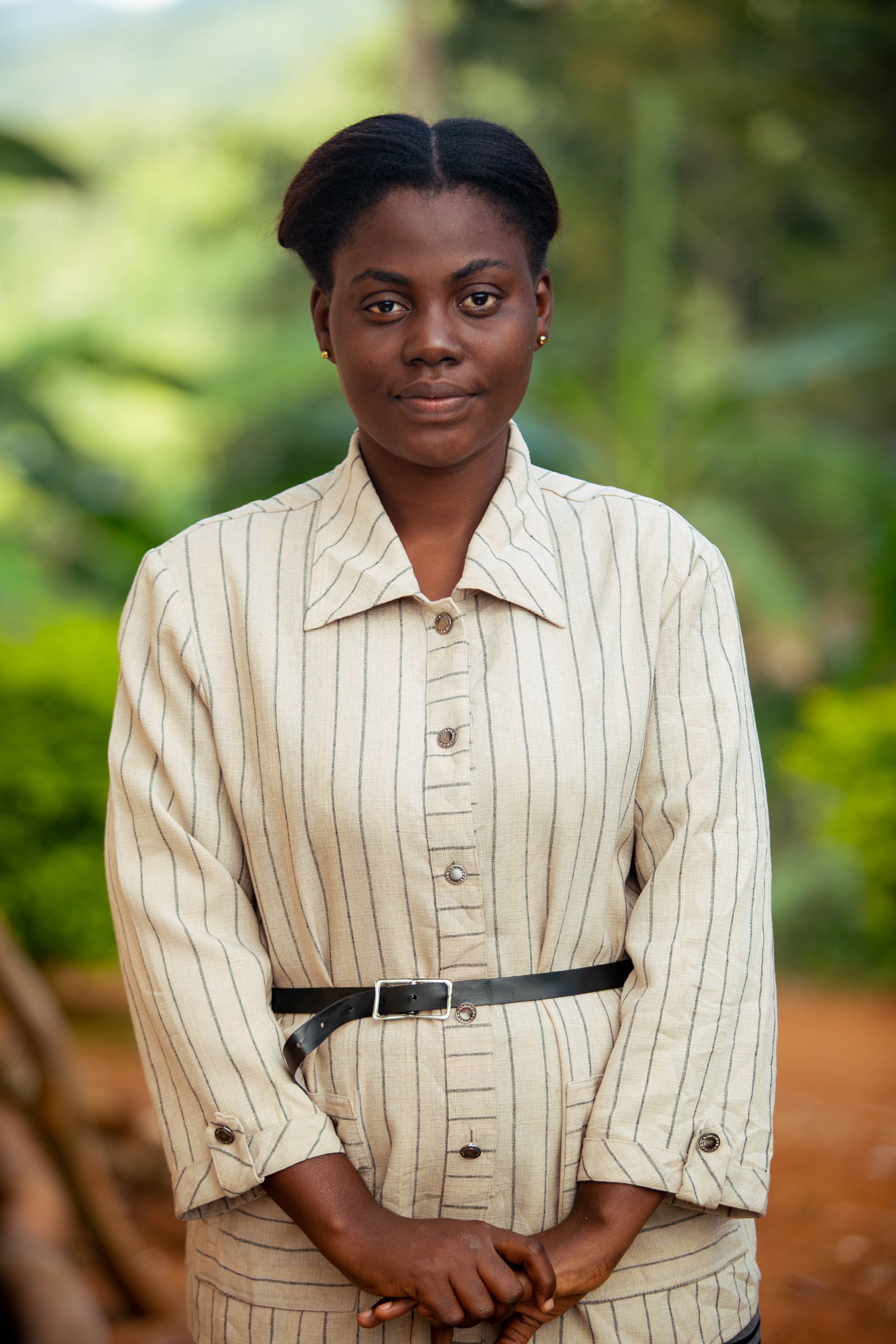 African woman in striped outfit posing outdoors in Amani, Tanzania.