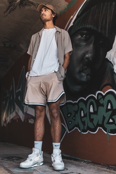 Young man in casual attire standing in front of vibrant graffiti in an urban tunnel.
