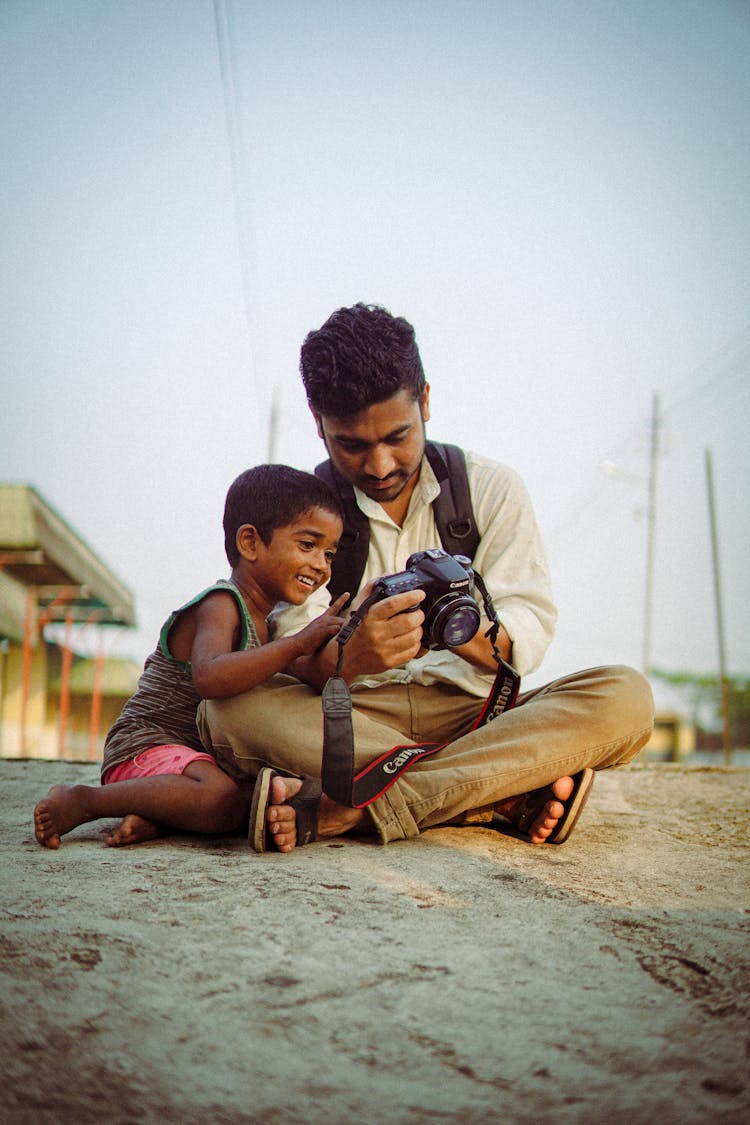 Man Showing A Little Boy A Picture On His Camera 