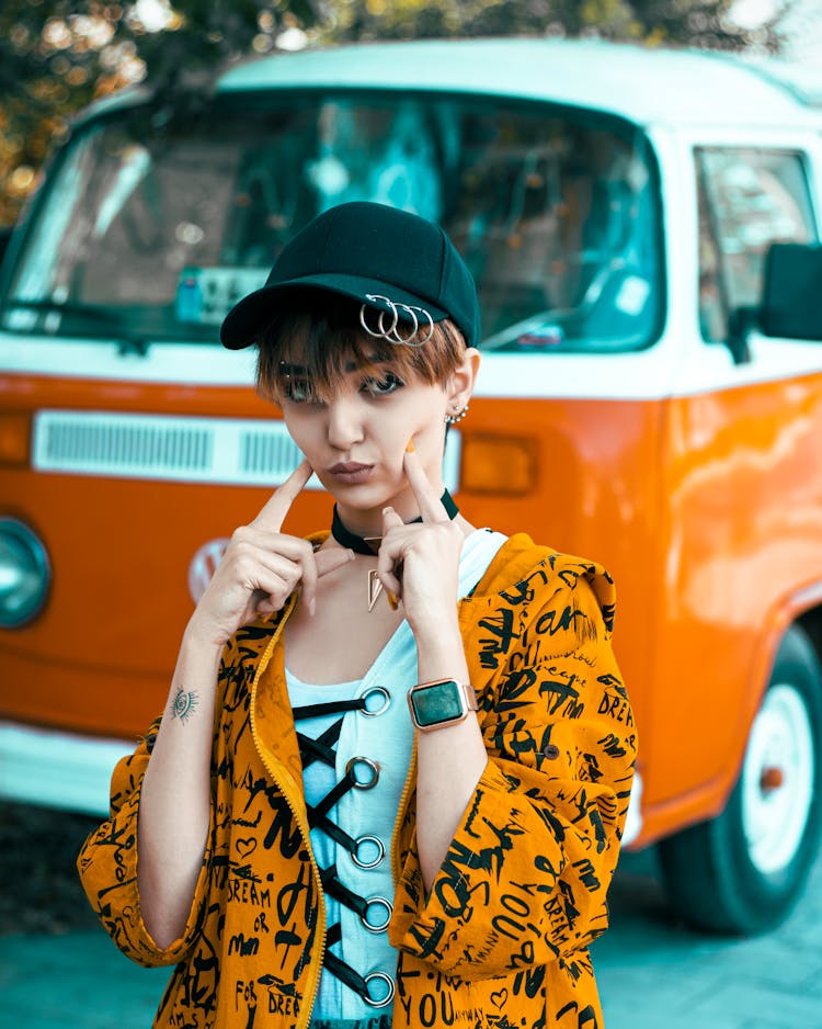 Photo Of A Woman In An Orange Sweatshirt Standing Against The Background Of An Orange Car