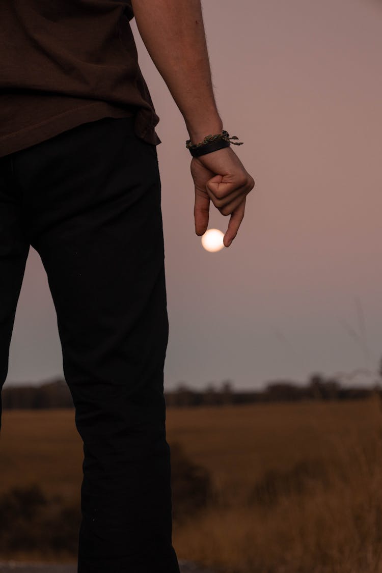 Close-up Of Man Holding Moon In Fingers