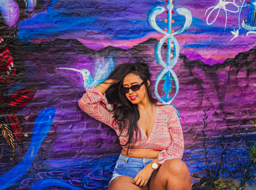 Free Stylish woman posing by an artistic, colorful urban mural wall. Stock Photo