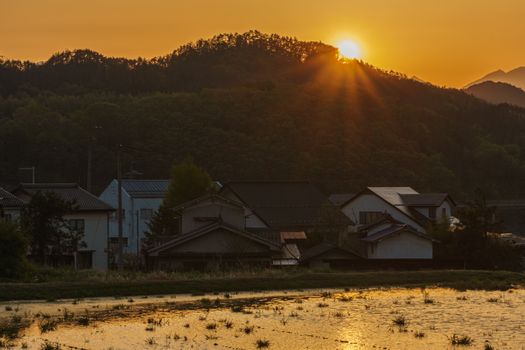 Peaceful sunset over a traditional village with hills in Chikuhoku, Nagano, Japan.
