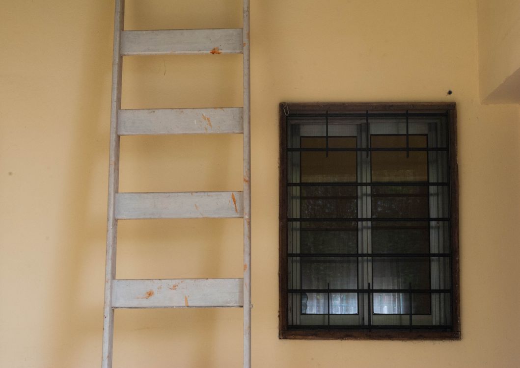A Ladder Near a Metal Window Frame on Yellow Wall · Free Stock Photo