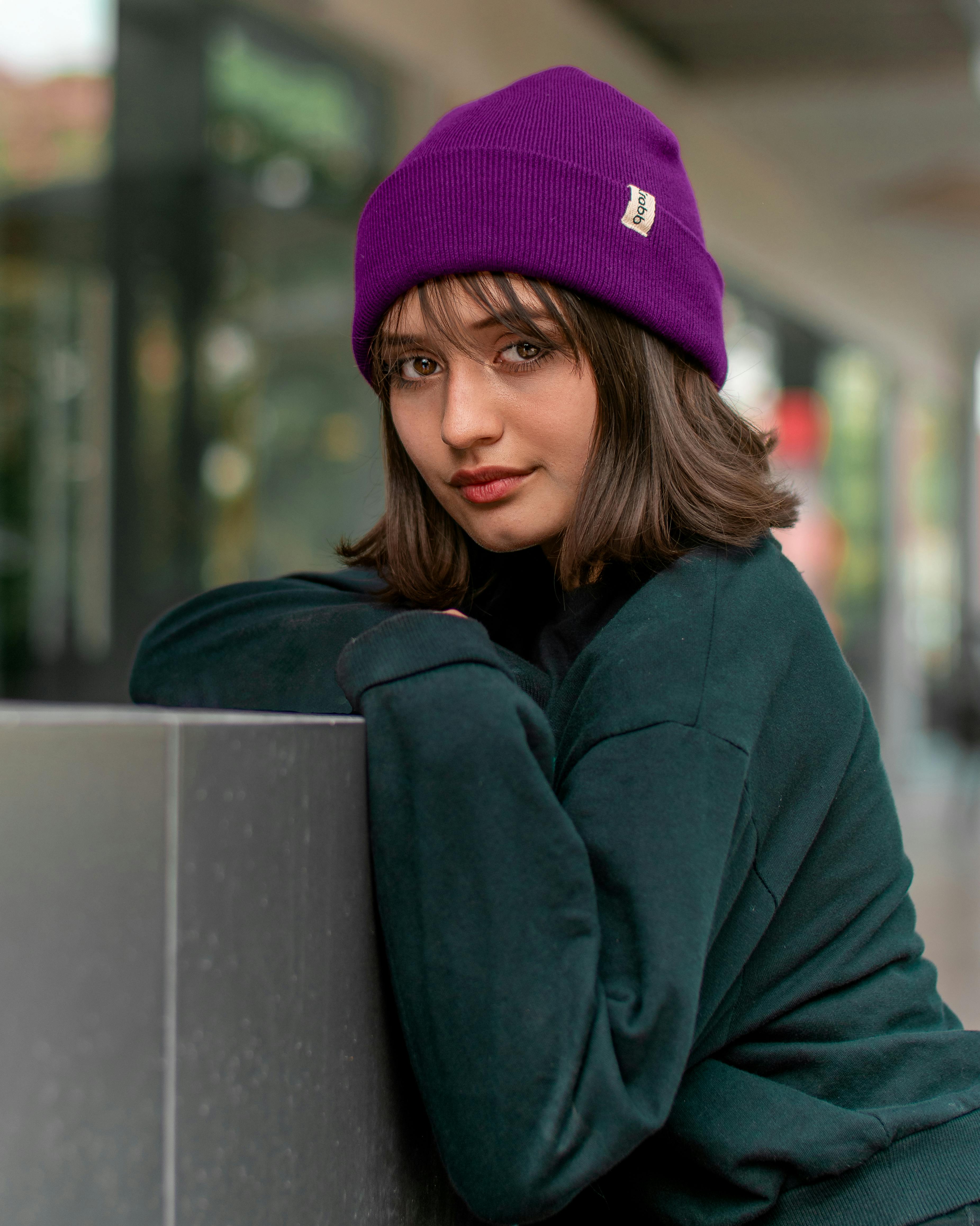 a teenage girl in a black jumper and a purple beanie hat