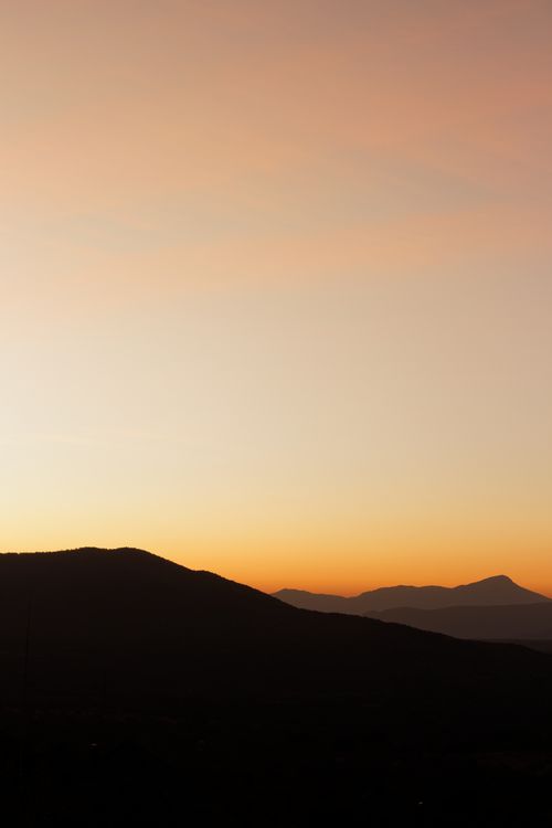 Free Capture of a mountain landscape at golden hour with a warm, dusky sky. Stock Photo