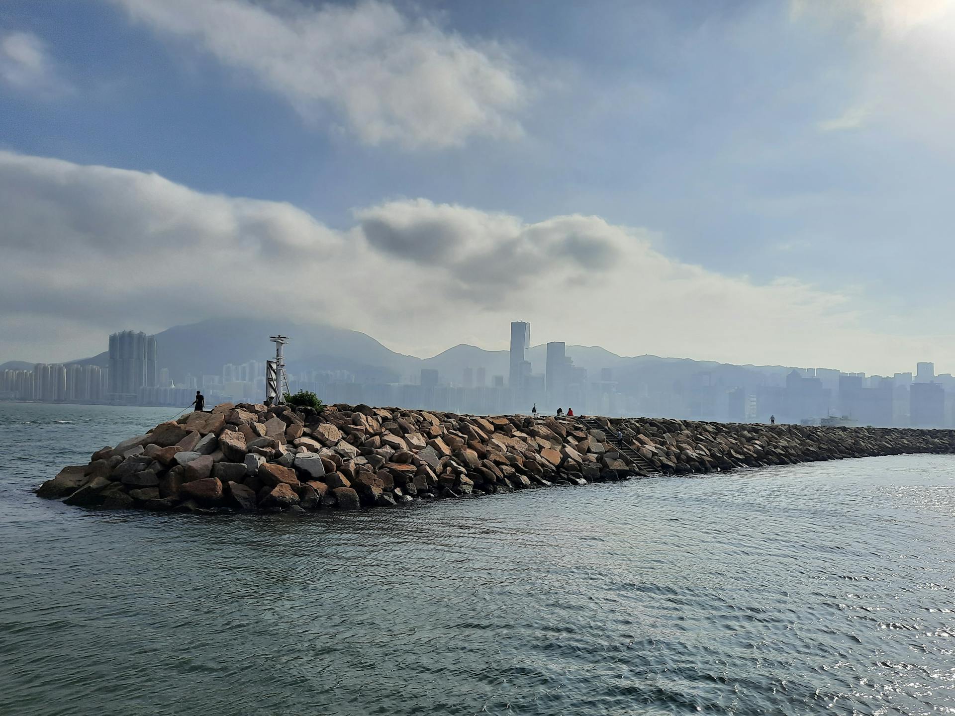 Beautiful city skyline view with a rocky breakwater under a bright sky.